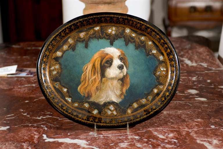 A small English Victorian era papier-mâché tray from the mid-19th century with hand-painted King Charles Spaniel and mother-of-pearl inlay. This exquisite English tray features, on a black background accented with gilded foliage and mother-of-pearl
