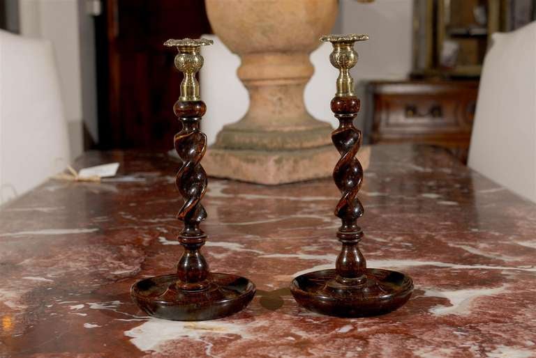 A pair of early Victorian mid-19th century oak barley twist candlesticks from Scotland, with brass thistle tops. Created in Scotland during the second quarter of the 19th century, each of this pair of candlesticks features a brass thistle top