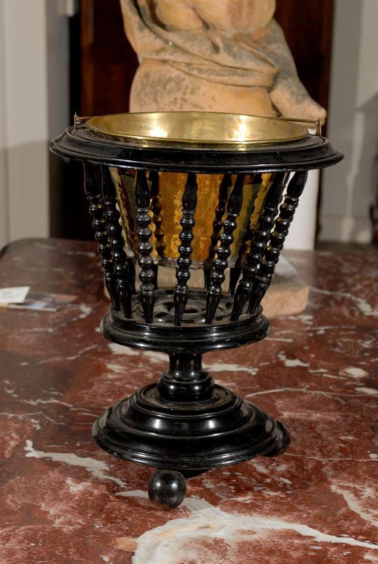 A Dutch ebonized wood jardinière from the mid 19th century, with brass liner, turned spindles and ball feet. Born in the Netherlands during the first half of the 19th century, this charming jardinière features a circular tapering body, accented with