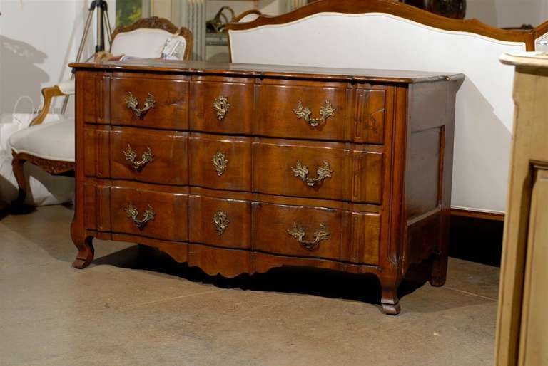 A Provençale French Louis XV period walnut commode en arbalète from the mid-18th century. Born in Provence in the 1750s during the reign of King Louis XV, this French three-drawer chest features a serpentine top sitting above three crossbow drawers.