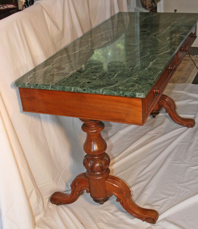 English Victorian walnut Library/Occasional/Consol Table with Italian mottled green marble top.  2 deep narrow Drawers.  Twin carved pedestals with acanthus leaf design.   All original including casters.