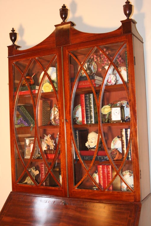 English Georgian mahogany Secretaire with satinwood stringing and rosewood embellishments.  Top bookcase section has 3 adjustable (or removable shelves) and the cupboard doors have a brass strip separating them. Astragal glaze glass front. The slope