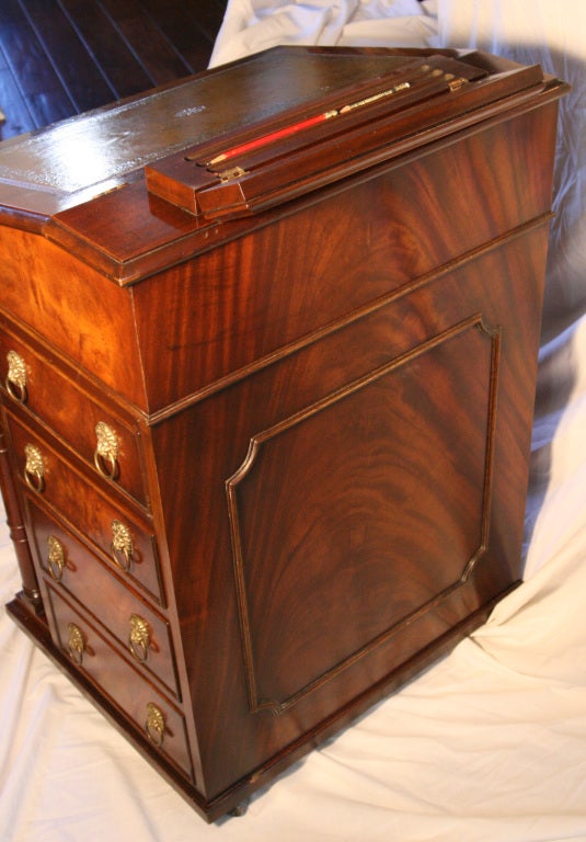 English mahogany Davenport personal desk.  Very convincing 20th century replica of 19th century.  Four Side drawers on the right with brass handles.  Pencil box on top of writing section. Slope writing surface with tan tooled leather with thistle