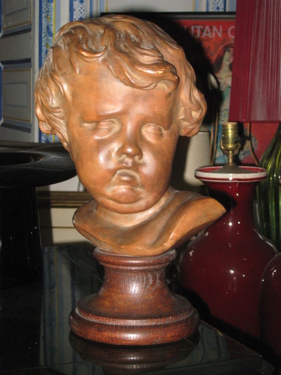 Terracotta sculpture of Putto on a polished oak base.
