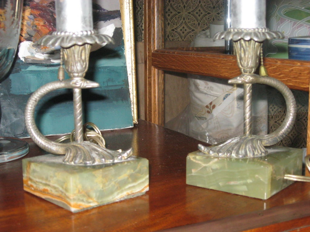Pair of serpent bronze boudoir lamps on marble bases with black paper shades.