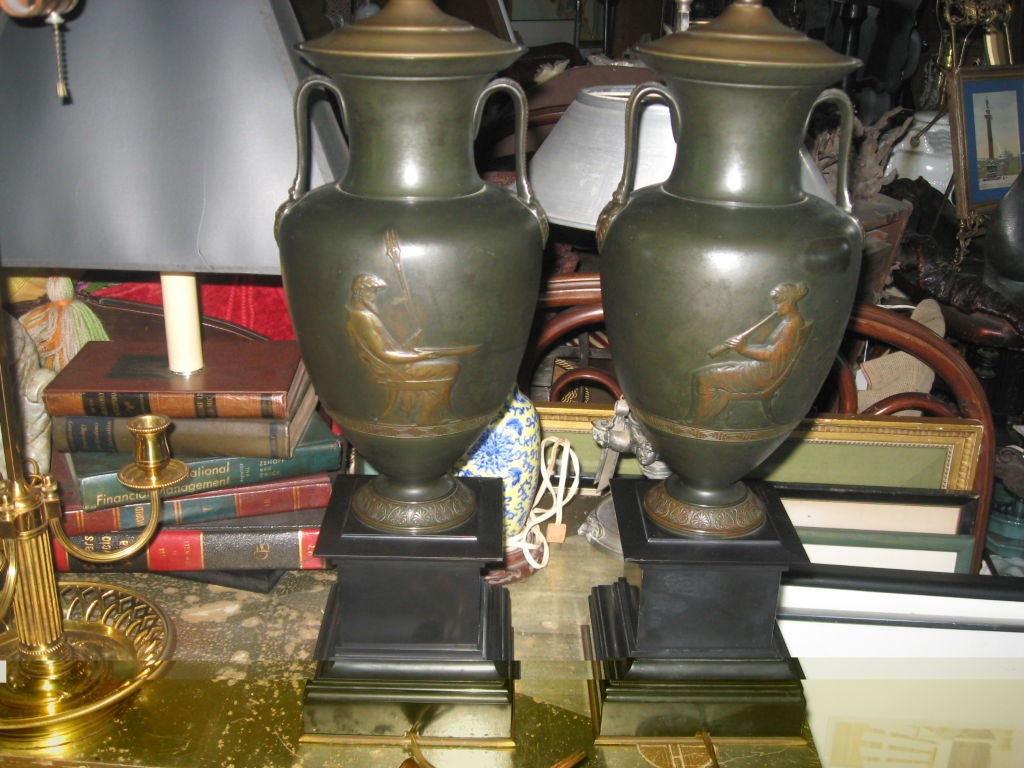 Zwei Urnen aus Bronze im neoklassizistischen Stil, die zu Lampen umfunktioniert wurden, montiert auf polierten Schiefersockeln.