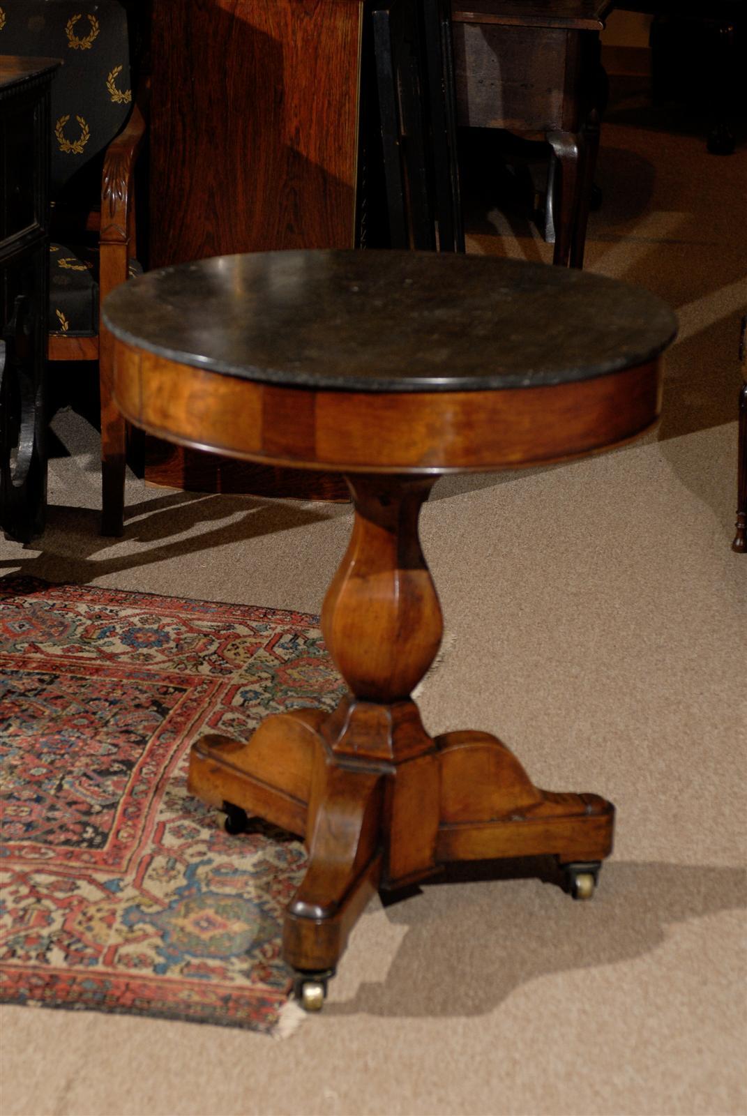 Early 19th century, Italian, walnut Gueridon with dark grey marble top and pedestal base resting atop brass castors.