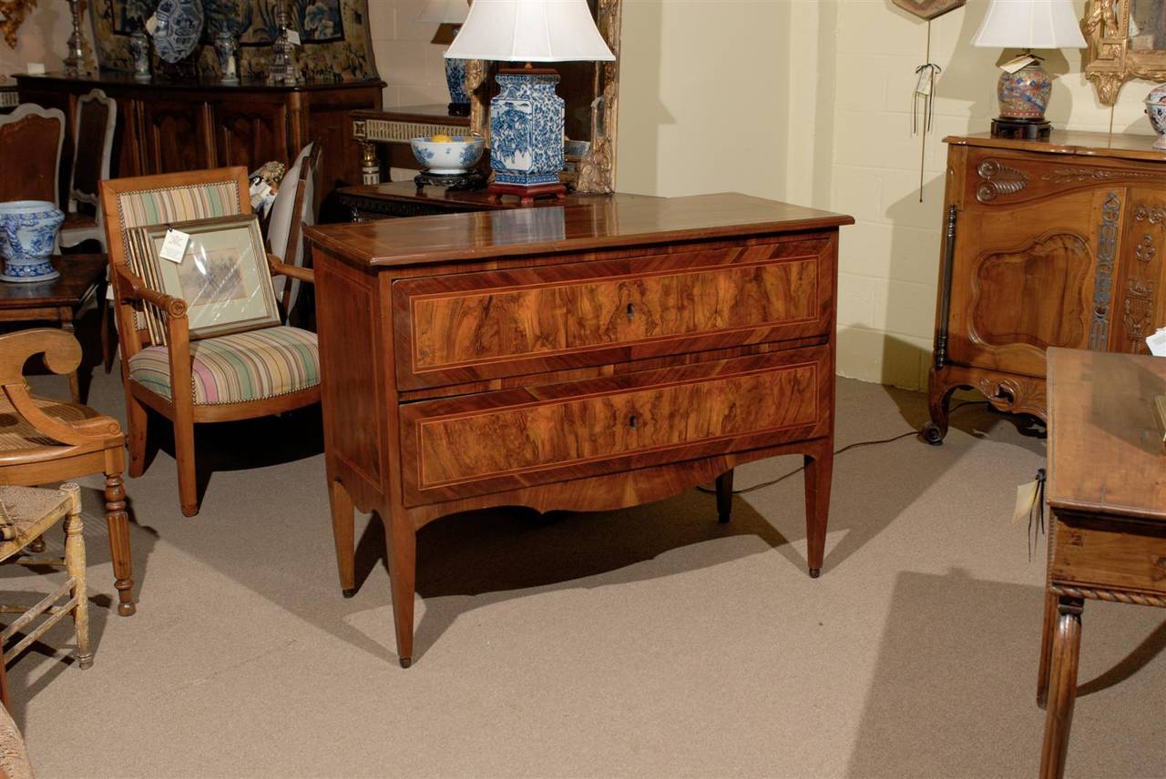 An Italian Neoclassical commode in walnut with 2 drawers, shaped apron and  square tapering legs.