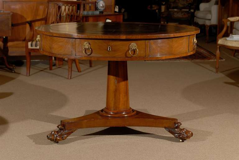 English mahogany rent table with four drawers and lion head pulls, black leather top and pedestal base. All resting on paw feet with brass castors. 

William Word Fine Antiques: Atlanta's source for antique interiors since 1956.
