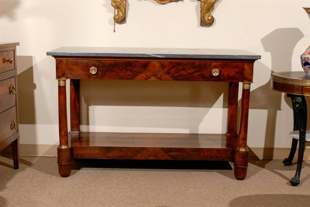 Long 19th century French Empire mahogany console with grey marble top and single long drawer affixed with ormolu pulls and column shaped legs with ormolu capitals.

William Word Fine Antiques: Atlanta's source for antique interiors since 1956.