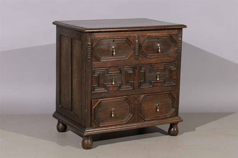 A petite Jacobean English style oak chest with 4 sliding drawers, brass pulls and bune feet. 

William Word Antiques: Atlanta's source for antique interiors since 1956.