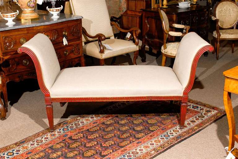 A neoclassical style red painted long upholstered bench with arms and fluted legs. 
 
William Word Fine Antiques: Atlanta's source for antique interiors since 1956.