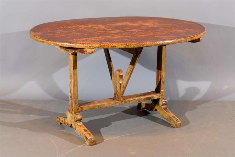 A rustic tilt-top wine tasting table with yellow and red worn painted finish. 

William Word Fine Antiques: Atlanta's source for antique interiors since 1956.