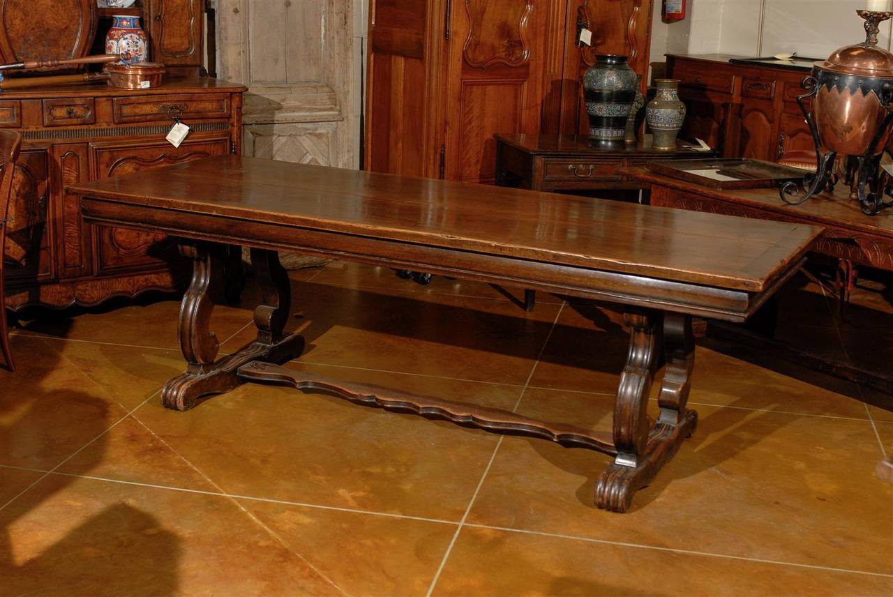 A 19th century French walnut dining table with lyre shaped legs and center stretcher.