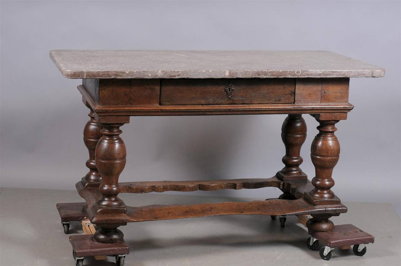 A Danish Baroque table in oak with fossilized stone top, drawer, baluster legs, stretcher and bun feet. 

William Word Fine antiques: Atlanta's source for antique interiors since 1956.