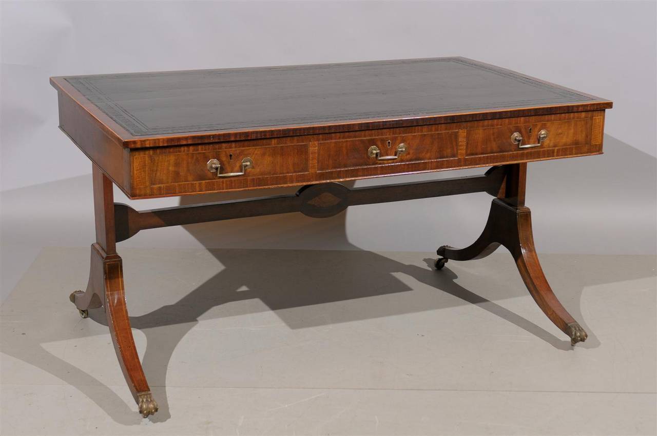 A 19th century English mahogany bureau plat with black leather top, three sliding drawers, splayed legs with stretcher and brass paw feet with castors. 

To view all of our inventory, please visit our website. 

William Word Fine Antiques: