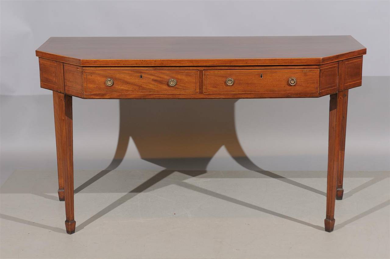 An early 19th century English mahogany serving table with cross-banded top, two drawers and square tapering legs with spade feet. 