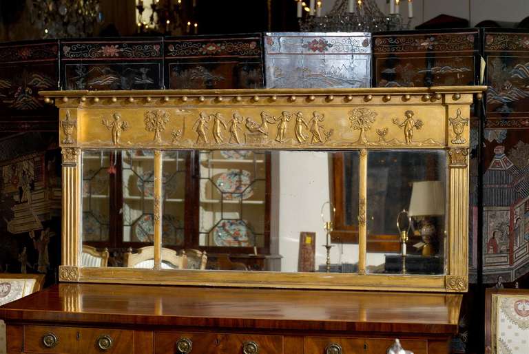 A gilt wood overmantel mirror in the Neoclassical style.