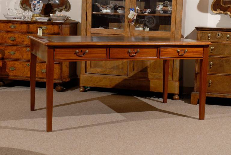 English mahogany writing table with brown embossed leather top and three drawers with brass bail pulls. 

William Word Fine Antiques: Atlanta's source for antique interiors since 1956.