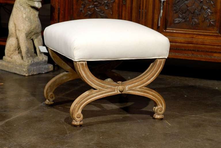 Dieser französische Polsterhocker im Vintage-Stil zeichnet sich durch einen exquisiten X-Rahmen aus:: der aus zwei umgekehrten Demilune-Stützen besteht. Die Füße sind schön geschwungen und leicht erhöht. Jede Beinstütze ist durch einen geschnitzten