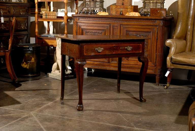 A mid-18th century English Georgian oak lowboy presenting a two-plank rectangular molded top over a frieze drawer whose figured wood and crossbanding nicely bring out the two brass swan-neck handles on engraved Chippendale escutcheon flanking the