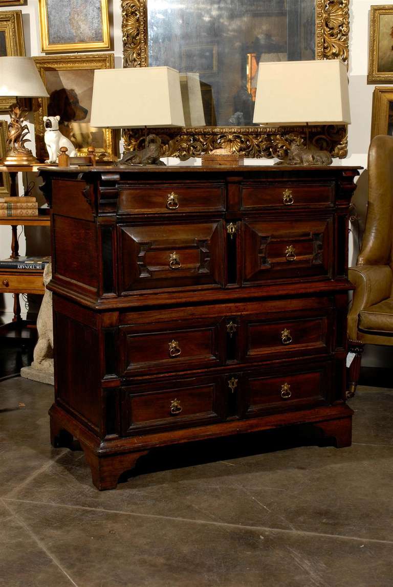 A mid-18th century large English chest of drawers with two cases and geometric carvings. This large 18th century English wooden chest of drawers is composed of two cases of equal size separated by a central molded cornice, each with paneled sides