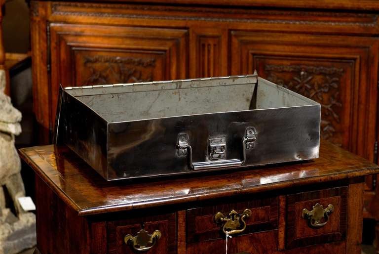 A burnished English steel box with handles from the turn of the century (19th to 20th). This stunning English steel box features two rigid, right angled hanging handles, one in the front and one on the side. This circa 1900 small trunk locks via a
