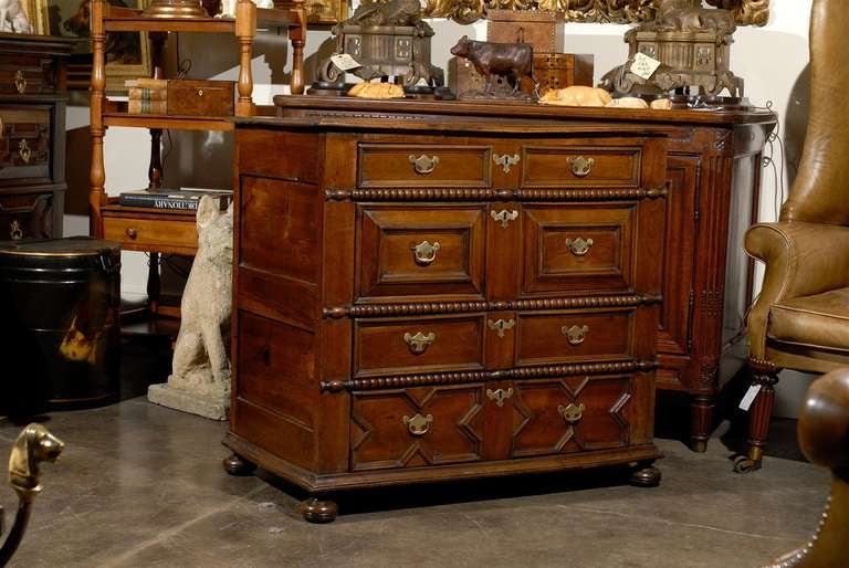 An English Georgian period Geometric front walnut five-drawer chest from the early 19th century with brass hardware. This English geometric front walnut chest from the early 19th century features a rectangular top with beveled edges over five nicely