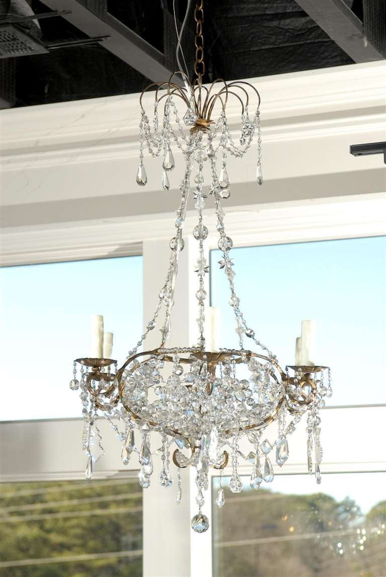 A French six-light crystal oval chandelier from the turn of the 19th century. This French crystal six-light chandelier from the turn of the 19th century features an oval gilt metal frame crowned with a crystal-beaded ring and ending in scrolls with