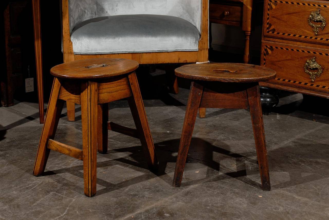 Two English oak stools with oval tops, splayed legs and side stretchers from the late 19th century. These English wooden stools are priced and sold separately. Each stool features a small oval top, pierced in its center with a swirly motif that