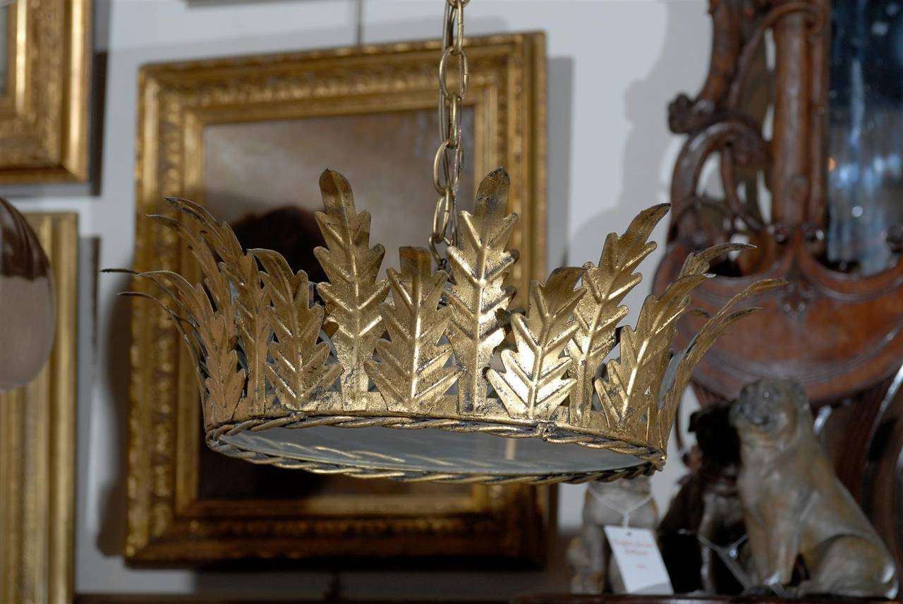 A Spanish vintage gilt metal two-light light fixture with frosted glass from the mid-20th century. This Spanish crown chandelier is adorned with elegant tall curved leaves on its surround, surmounting a braided rim. Two-light bulbs are secured