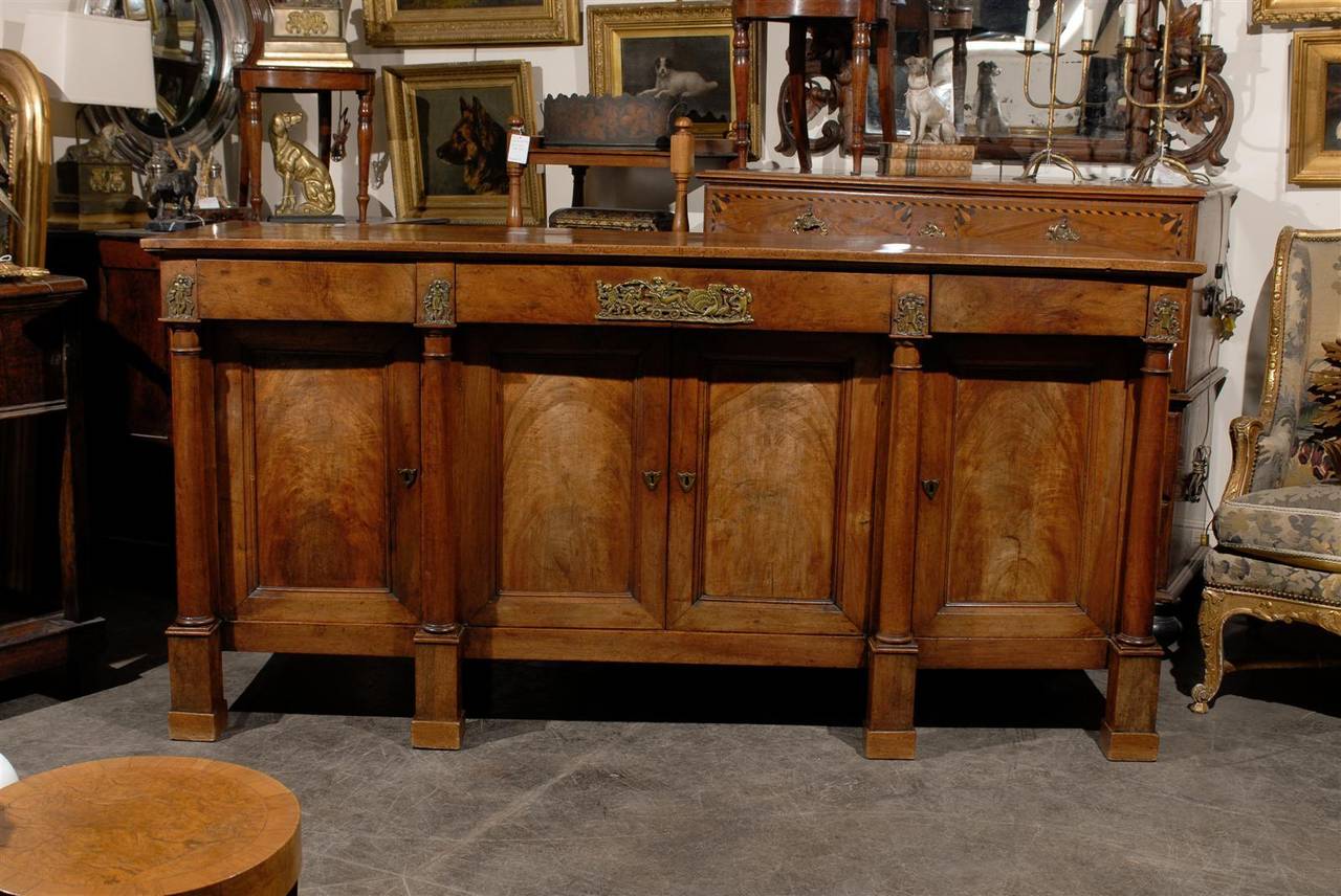 This exquisite French Empire period walnut enfilade from the early 19th century features a rectangular top over four doors. Four Doric columns give rhythm to the recessed façade. To achieve perfect symmetry, two columns flank the two central doors,