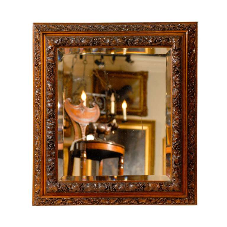 This English mirror from the late 19th century features a central bevelled glass, set inside a beautifully carved wooden frame. The richly carved sections are separated from each other by a thin molding, creating a nice respiration between them. The