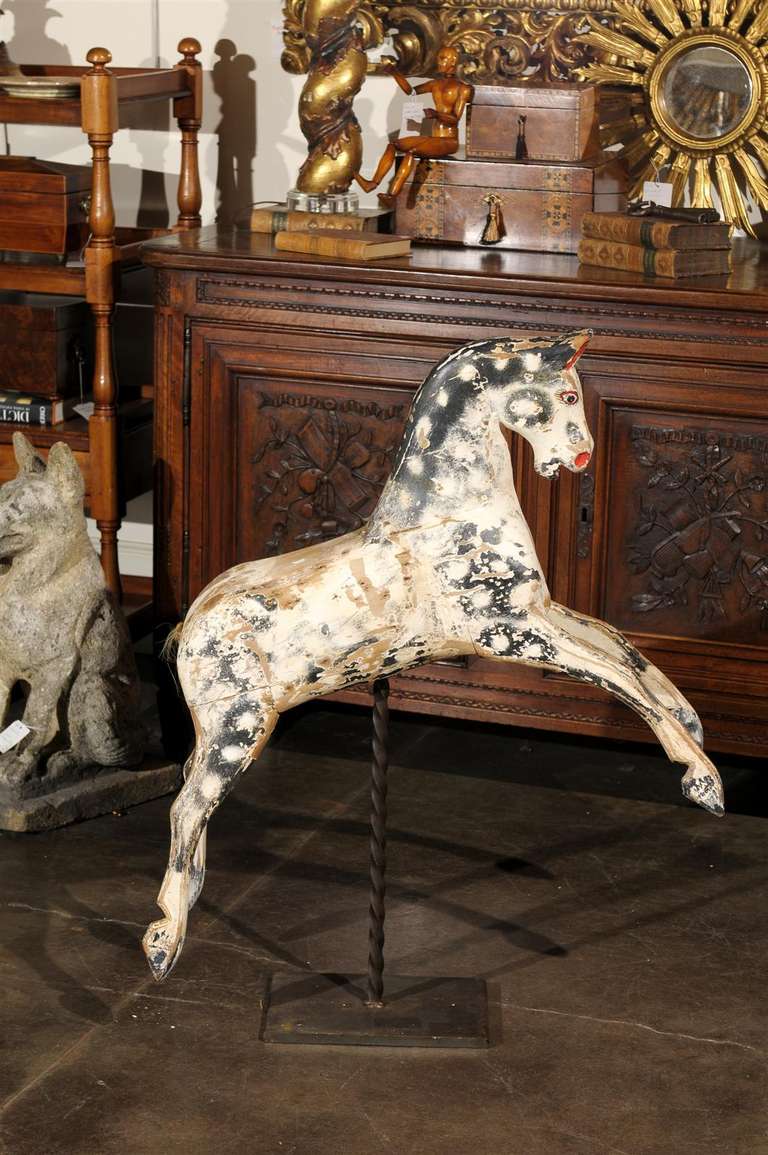 An English painted horse from the mid-19th century on new custom iron stand. This energetic large sized horse is painted black with white spots. It sits on a twisted iron stand yet somehow seems to be in motion, perhaps leaping over a fence. This