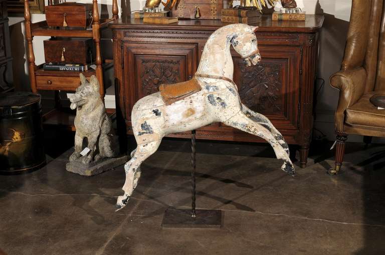 English large wooden horse on new custom twisted iron stand. This English large wooden horse with saddle, circa 1900, sits atop a heavy duty twisted metal stand. This horse seems to be in a whimsical mood as he leaps off of all four legs. The mane