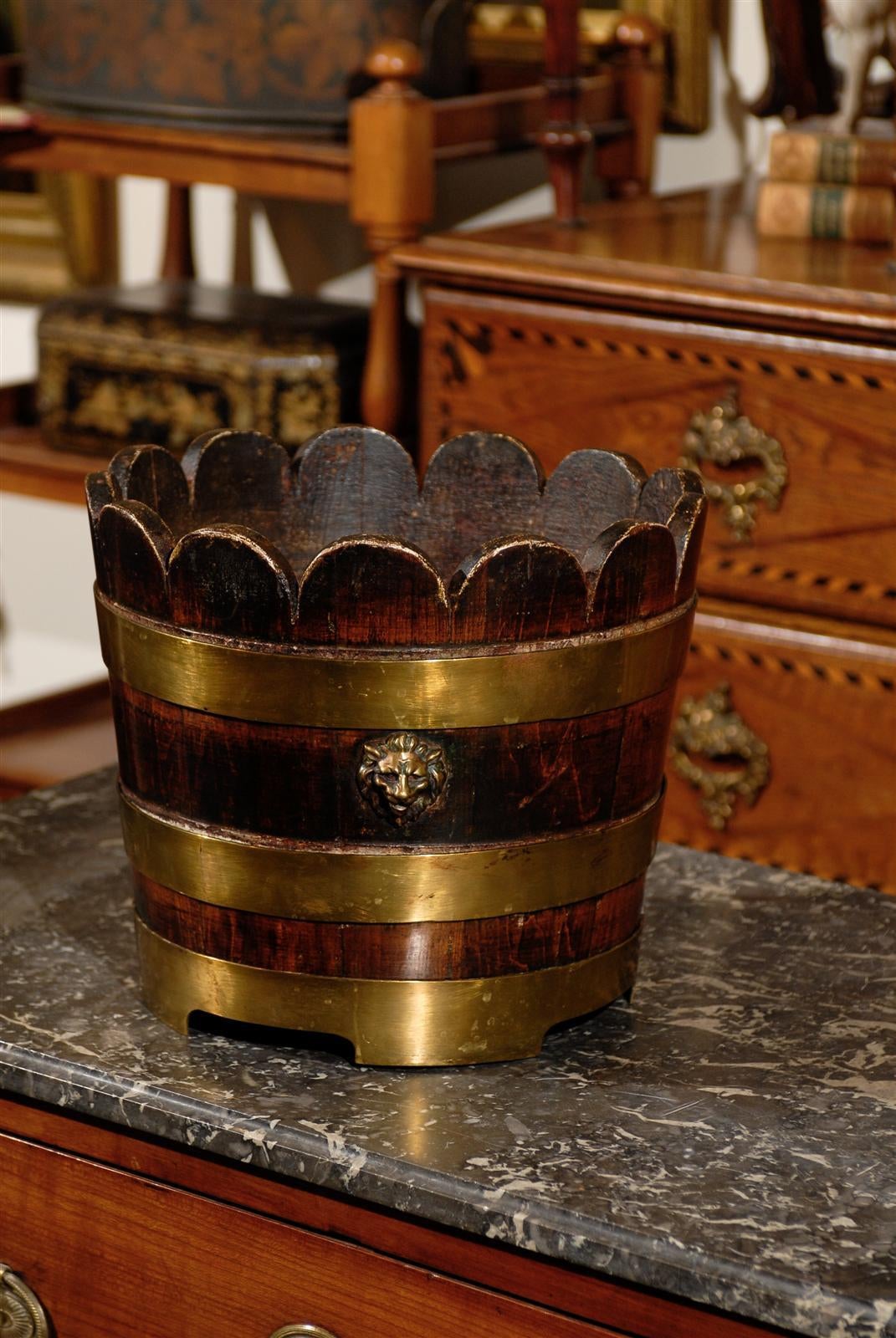 Early English wooden bucket with brass bands. This scallop topped English bucket features a nicely stained dark exterior and a lighter, natural interior. The wood of this bucket, circa 1900, is secured by three brass bands, the top of which has been