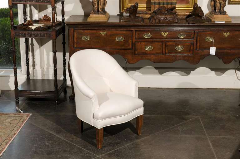 Early 20th century French upholstered barrel back child's chair. This French child's chair from circa 1920 features a light color upholstery wrapping the entirety of the chair, except for the four dark hardwood legs of straight shape in the back and