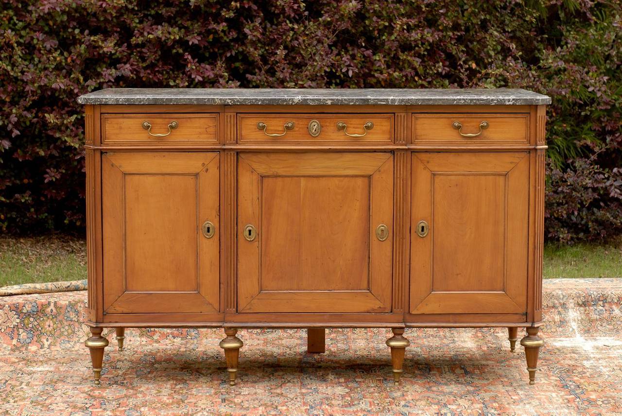 This French mid-19th century walnut buffet features a grey and white veined marble top with beveled edge and canted corners in the front, over a beautiful honey color walnut body with great patina. Three hand-cut dovetailed drawers are placed atop