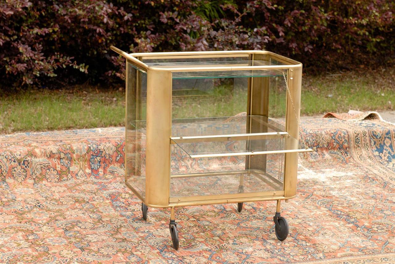 Brass cart with large wheels and glass shelves.
