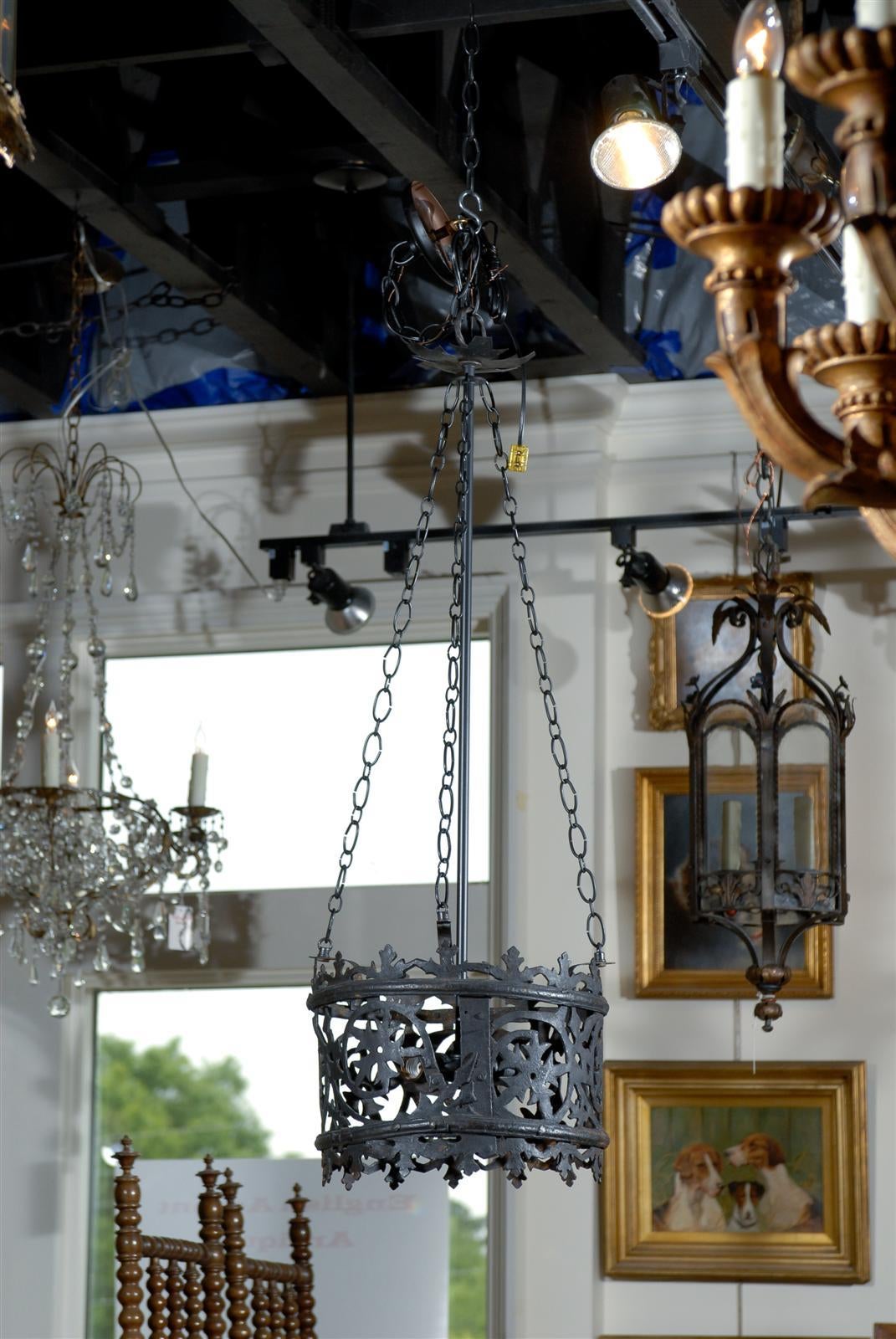 An Italian wrought iron chandelier with frosted glass from the mid-20th century. This round Italian chandelier features an elegant filigreed drum with a stylized fleur-de-lis decoration on both the top and bottom as well as a snowflake motif in the