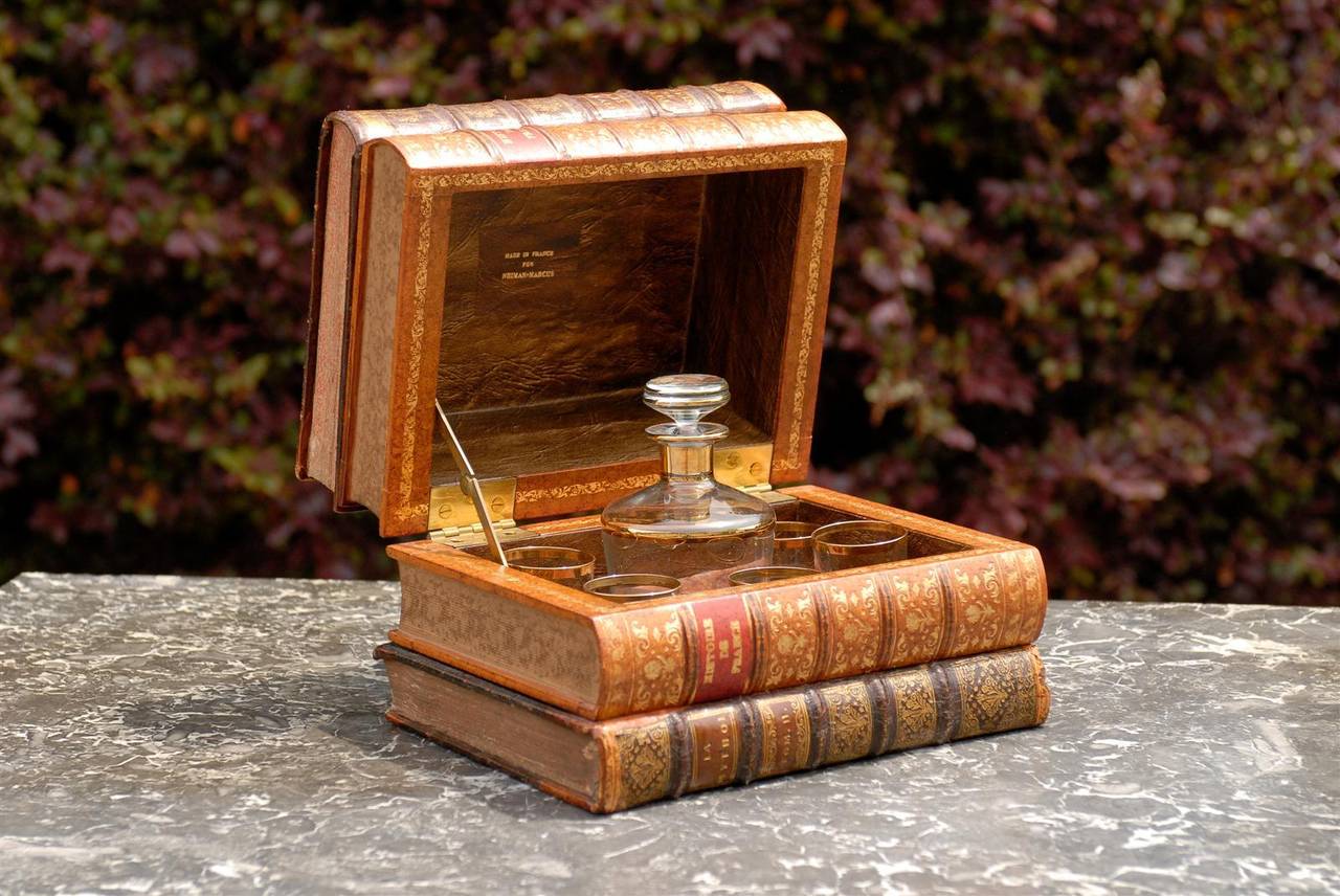 A French faux book leather decanter made for Neiman Marcus in the early part of the 20th century. At first glance this amazing decanter looks like a simple stack of books, only to reveal a crystal bottle and five glasses with gold rims when the top
