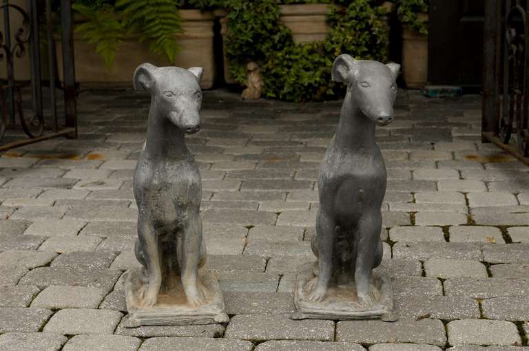 A pair of midcentury American lead dogs, obediently sitting on cushions. This adorable pair of dogs, circa 1930, was born in the United States and features two greyhound dogs seated on cushions and smelted in lead. In the 1930s during the Art Deco