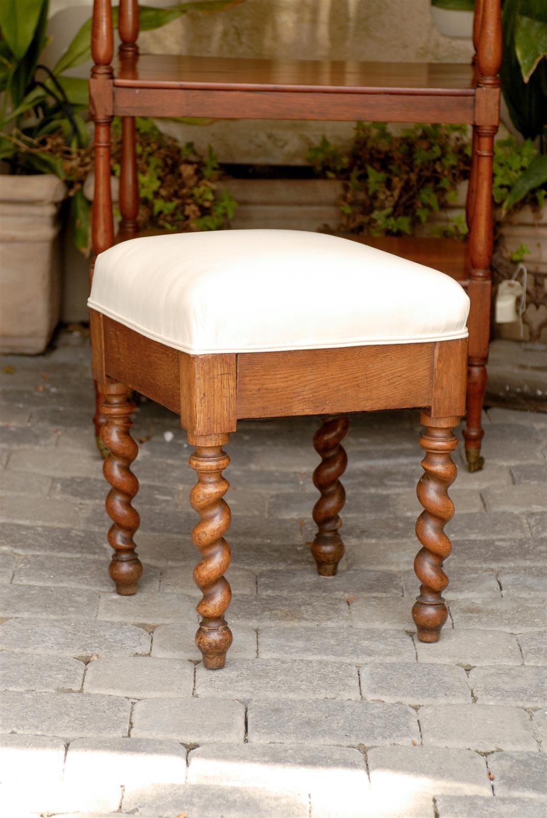 A French barley twist leg stool from the late 19th century. This French stool features four light brown barley twist legs supporting a simple skirt and a high cushion. The Barley twist style, while very popular in 19th century Europe actually