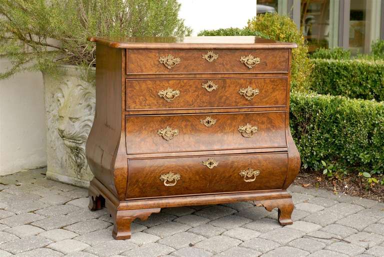 An 18th century Dutch Chippendale burl wood chest of four drawers raised on bracket feet with a bulging bottom and serpentine sides. The shaped rectangular molded top rests upon four graduating drawers, each adorned with a brass keyhole escutcheon