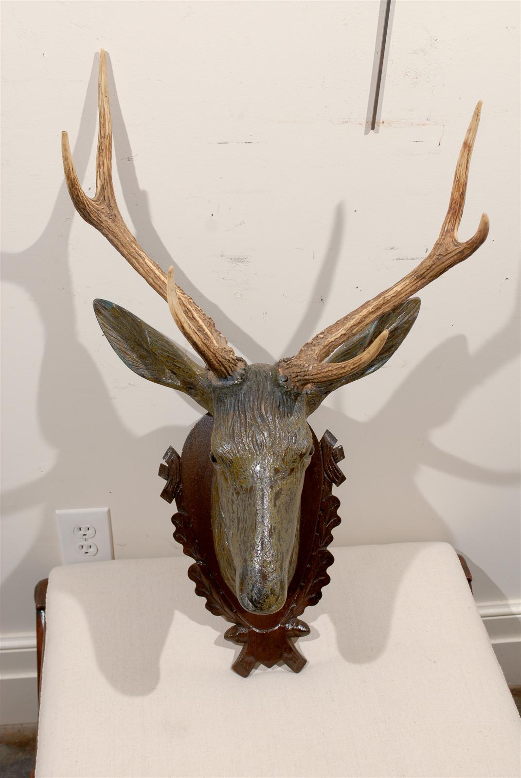 Carved stag head with antlers and old paint on carved plaque.