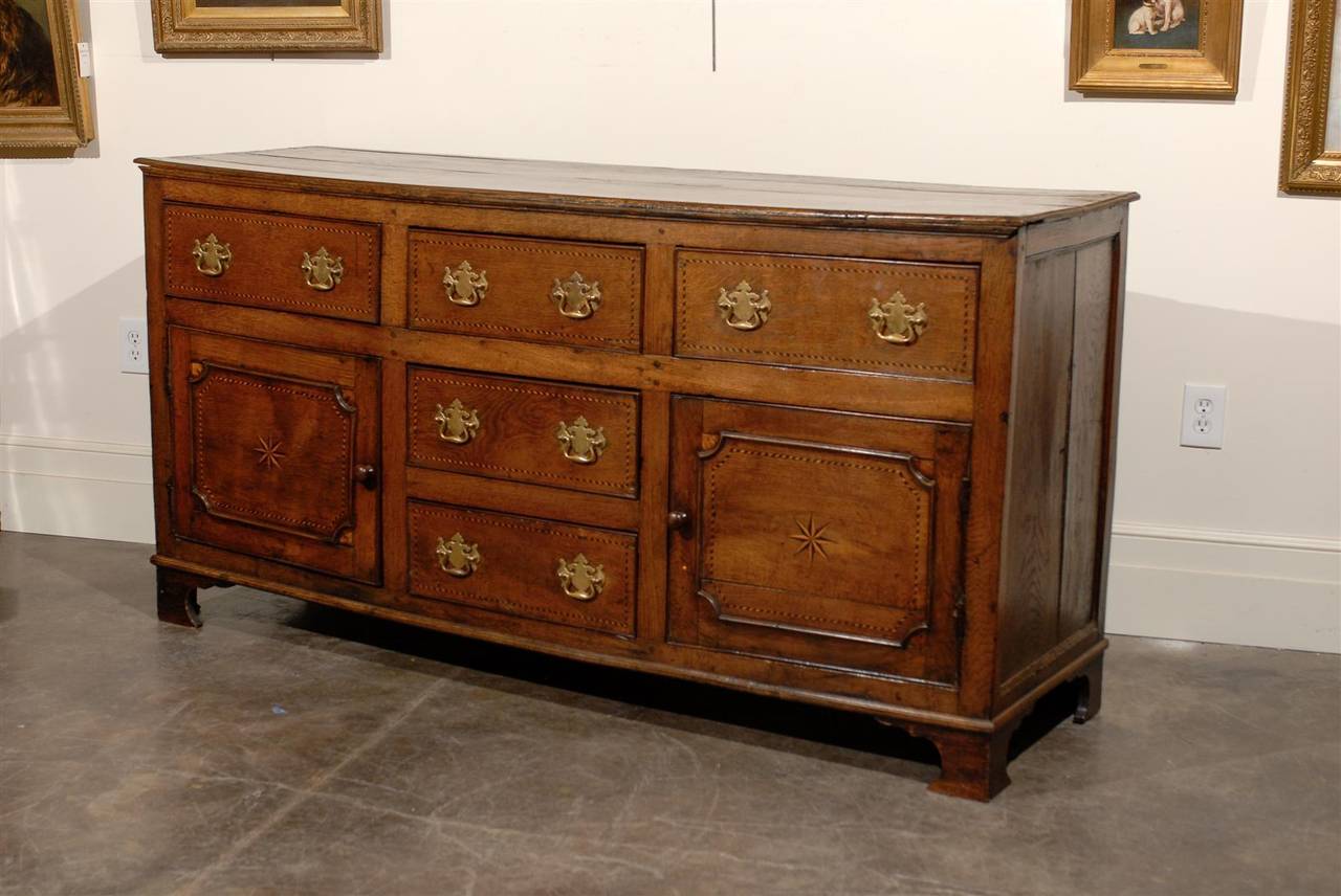 An English George III period dresser base with inlaid banding, doors and multiple drawers from the late 18th century. This English oak server from the late 18th century features a rectangular planked top sitting above a perfectly organized facade.