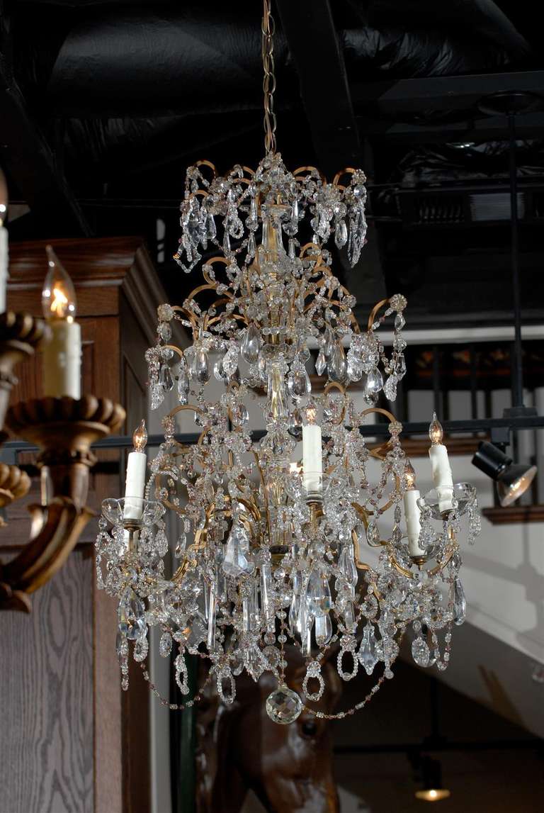 This French crystal six-light chandelier from the mid-20th century features a central crystal column gilded on the inside. The gilded armature supports a great variety of crystals, spear shaped, Swedish drops and small rosettes among others,
