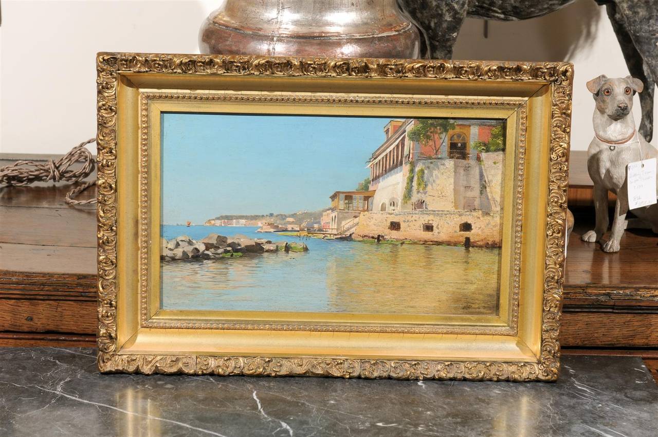 A continental coastal scene painted on a wood in giltwood frame from the 19th century. This painting suggests a Mediterranean coastal town, possibly someplace in the Côte d'Azur or Liguria or some other place where the sun seems to turn life into a