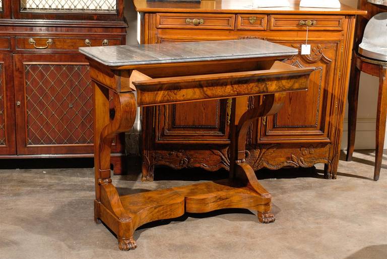 French 19th century Louis Philippe style walnut console featuring a rectangular grey marble top over an ogee molded (or doucine) frieze drawer assembled with finger joints. This piece rests on scroll supports merging with two rear square legs,