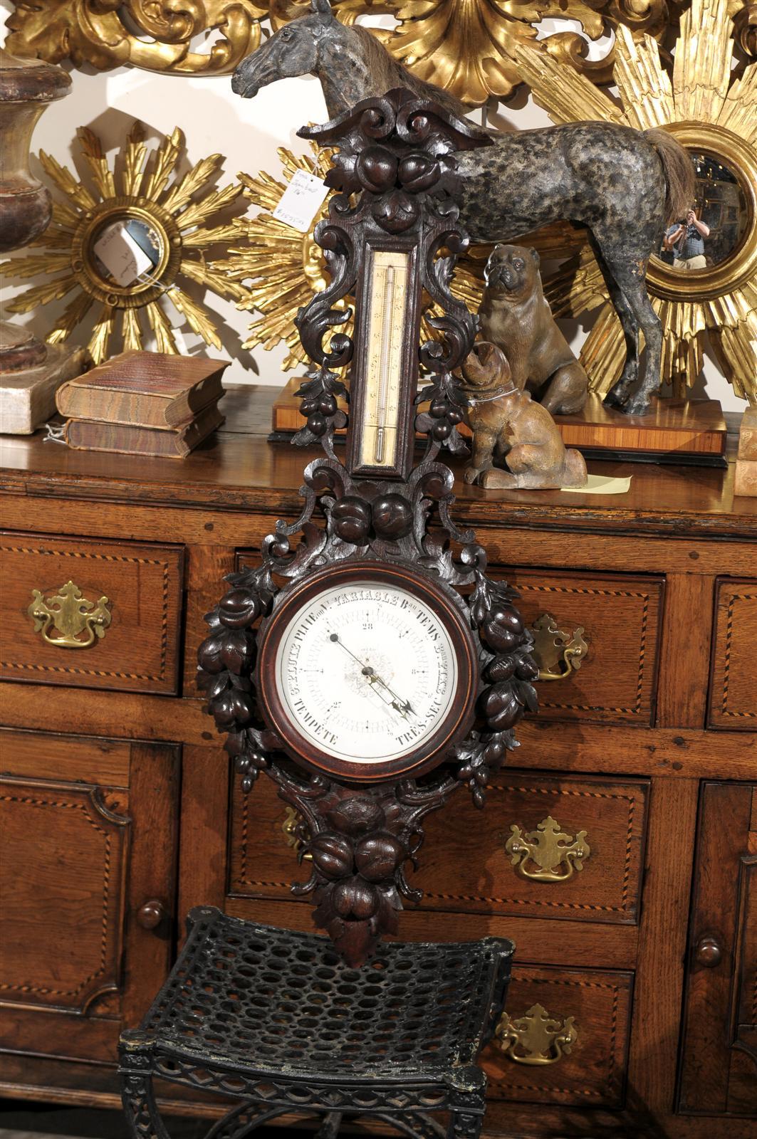 This French Black Forest barometer from the turn of the century (19th to 20th) features a wonderfully hand-carved frame, made of various foliage and volutes. Contrasting nicely with the dark finish of the carved wood, the barometer finds its place
